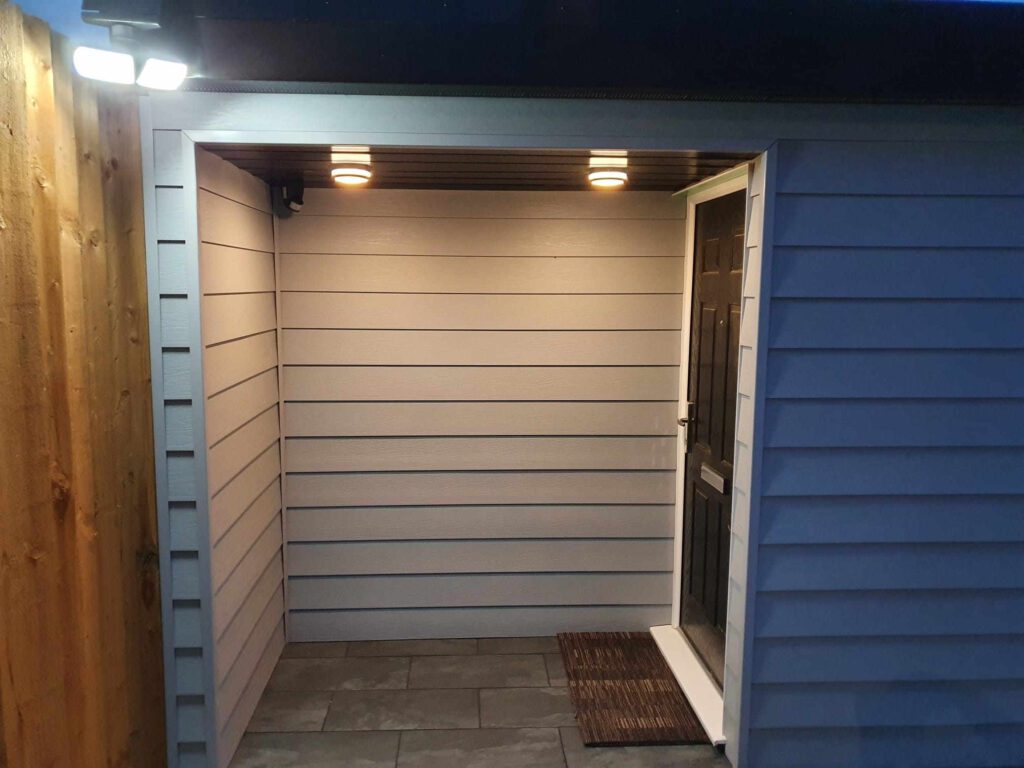 Cladded frontage of extension. Grey cladding, 2 large spotlights in front of the main door.